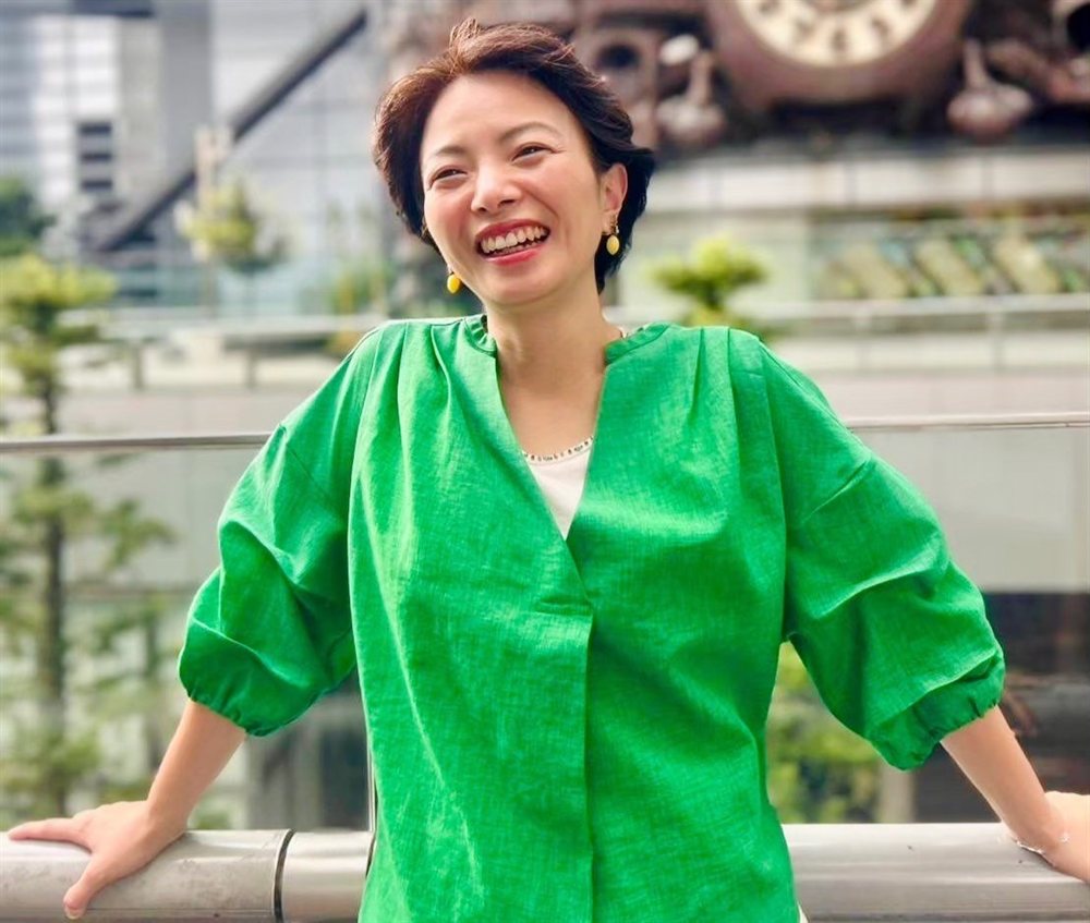 藤曲めぐみのプロフィール写真。緑色のトップスで笑っている様子。